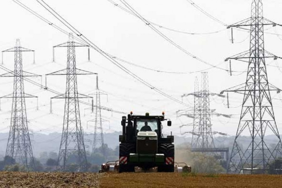 A farmer works in a field surrounded by electricity pylons in Ratcliffe-on-Soar, in central England, Sep 10, 2014. REUTERS/Darren Staples