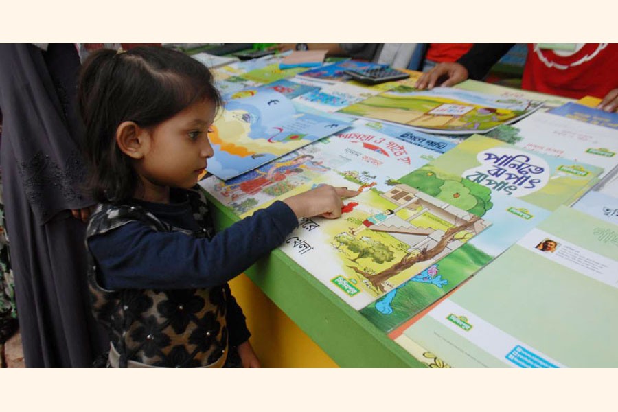 A children is browsing books in the Ekushey Book Fair. Learning Bangla correctly becomes a big challenge for the young generation	—UNB Photo