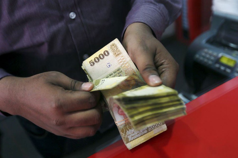 A man counting Sri Lankan rupees at a money exchange counter in Colombo –Reuters file photo