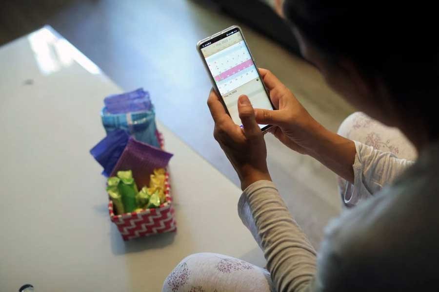 Raquel del Rio, 36, who works in police forces, posing as she observes a period calendar tracker app on her mobile phone at her home in Madrid of Spain on May 16 this year –Reuters file photo