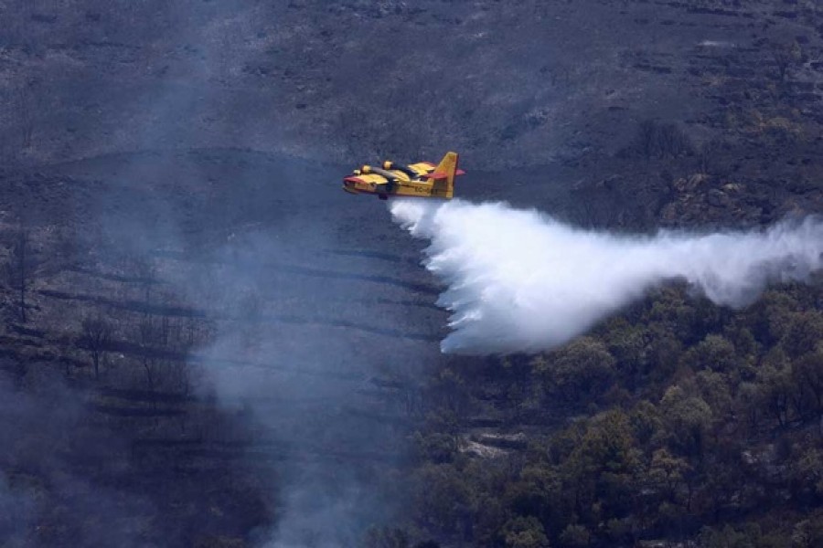 An aeroplane drops water onto a wildfire in Murca, Portugal, Jul 20, 2022. REUTERS/Pedro Nunes