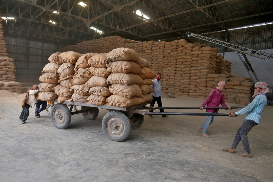 Labourers move a cart loaded with rice bags inside a food processing unit, which was reopened after weeks-long shutdown to slow the spread of coronavirus disease (COVID-19), on the outskirts of Ahmedabad, India, Apr 20, 2020.REUTERS