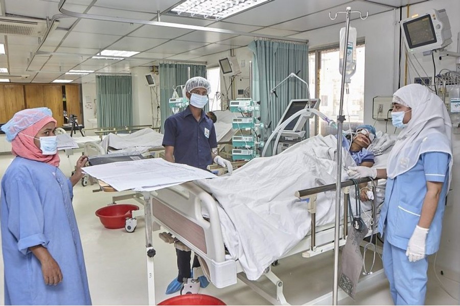 A patient, surrounded by caregivers, at an ICU bed in Dhaka. 	—Collected Photo