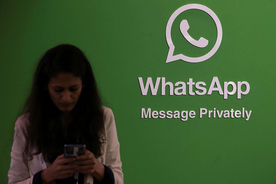 A woman uses her phone next to a logo of the WhatsApp application during Global Fintech Fest in Mumbai, India on September 20, 2022 — Reuters/Files