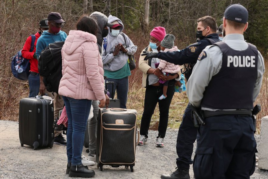 Asylum seekers talk to a police officer as they cross into Canada from the US border near a checkpoint on Roxham Road near Hemmingford, Quebec, Canada on April 24, 2022 — Reuters/Files