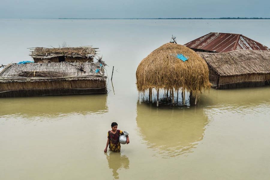 A woman affected by floods in Bangladesh wades through waist-deep water in search of clean water. (UNOCHA)