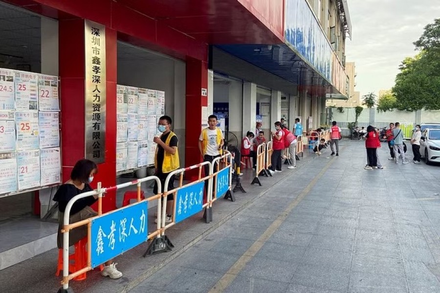 People stand outside agencies advertising factory job openings in Shenzhen's main factory recruitment hub in Longhua district, Guangdong province, China, Oct 20, 2022. Reuters