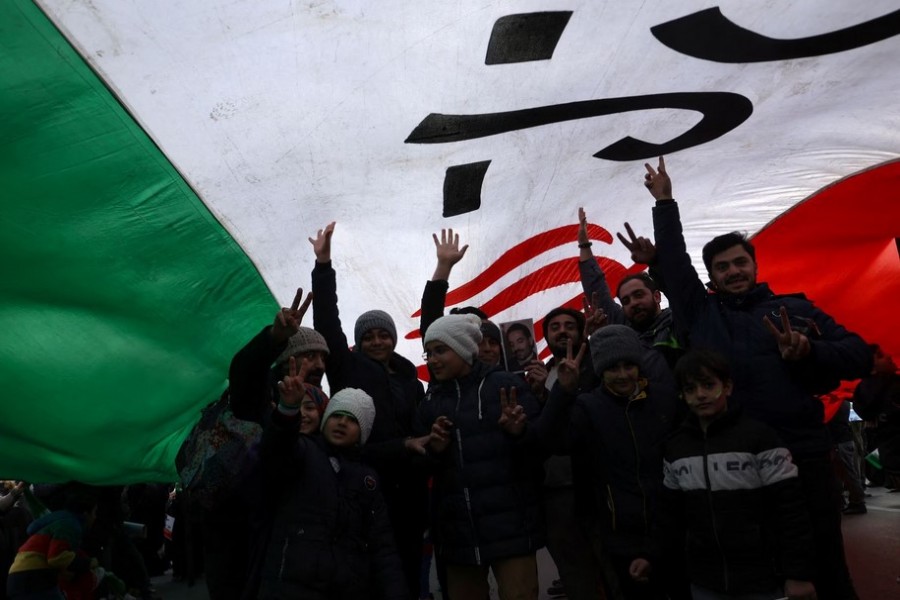 Iranians are seen under a large flag of Iran during the 44th anniversary of the Islamic Revolution in Tehran, Iran, February 11, 2023. Majid Asgaripour/WANA (West Asia News Agency) via REUTERS