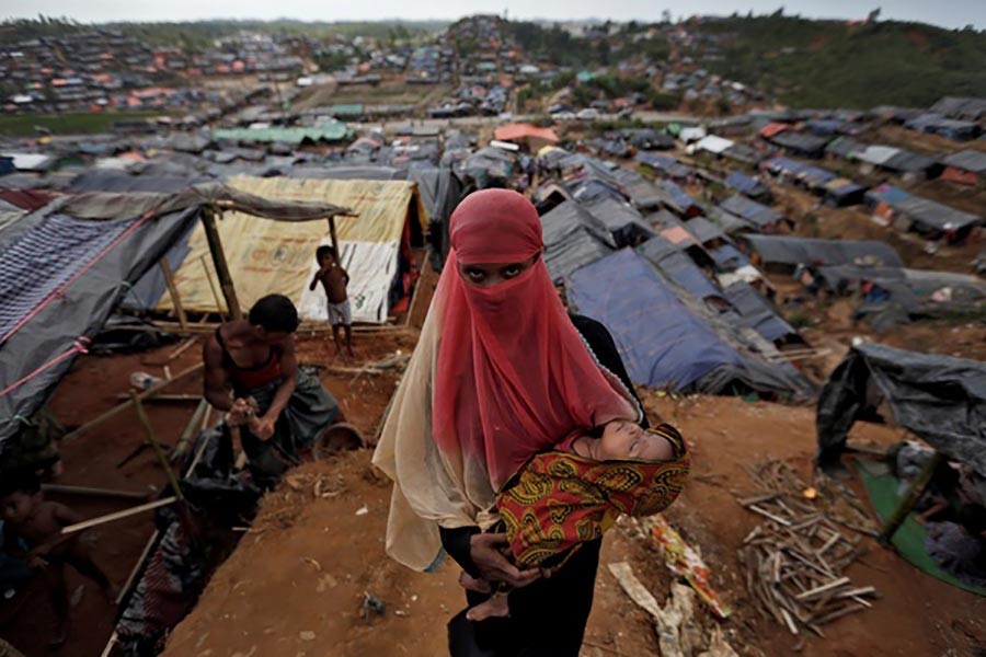 A Rohingya refugee carries her child in a refugee camp in Cox's Bazar of Bangladesh on Sunday. -Reuters Photo