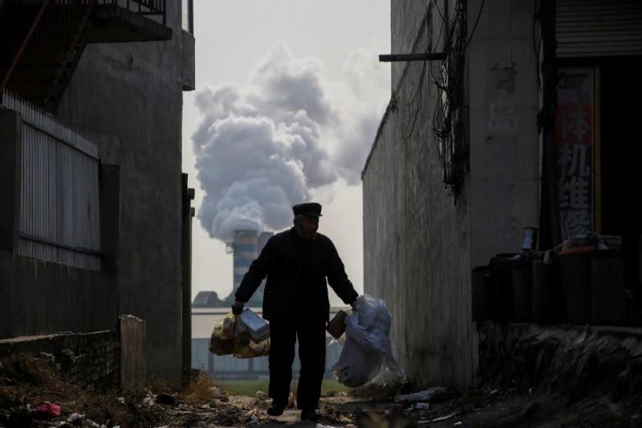 A man collects recyclables from an alley as smoke billows from the chimney of a factory in rural Gaoyi county, known for its ceramics production, near Shijiazhuang, Hebei province, China December 7, 2017. - Reuters file photo