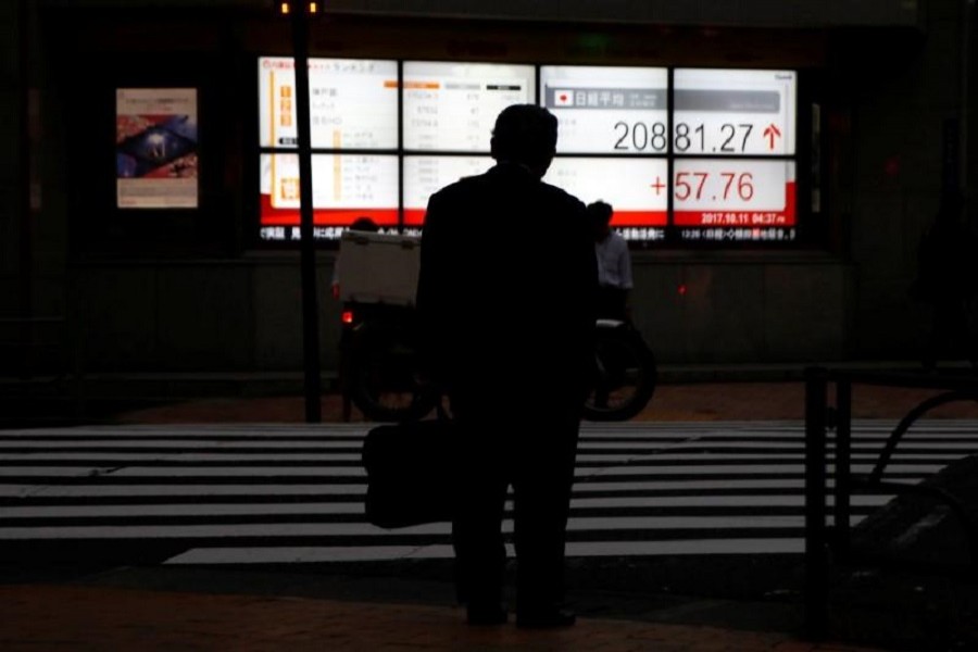 A man stands in front of an electronic board showing Japan's Nikkei average outside a brokerage in Tokyo, Japan October 11, 2017. Reuters/File Photo