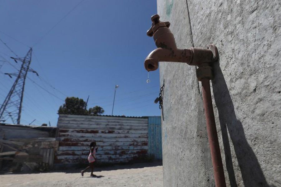 Residents walk past a leaking communal tap in Khayelitsha township, near Cape Town, South Africa, December 12, 2017. (REUTERS)