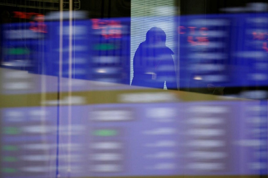 A visitor is seen as market prices are reflected in a glass window at the Tokyo Stock Exchange (TSE) in Tokyo, Japan, February 6, 2018. Reuters