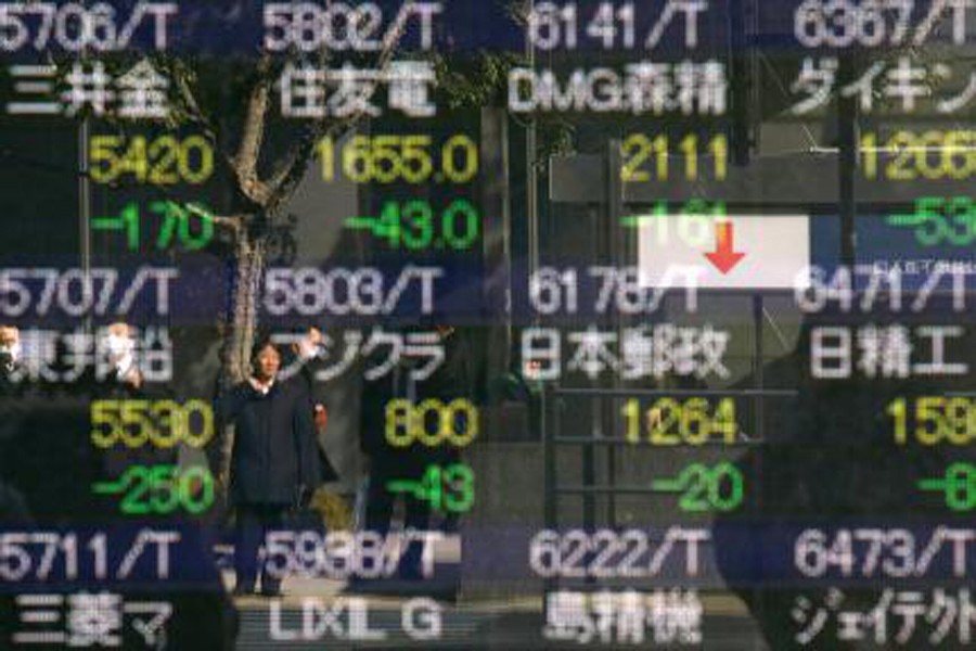 A man is reflected in an electronic stock quotation board outside a brokerage in Tokyo, Japan February 9. Reuters/File Photo