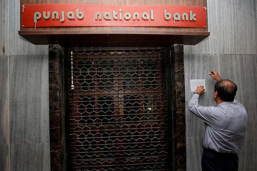 A man tries to remove a notice pasted on the wall of a Punjab National Bank branch after it was sealed by India’s federal police in Mumbai, India, on February 19, 2018. - Reuters photo
