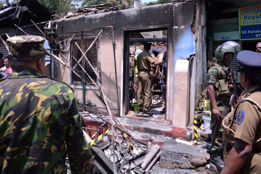 Sri Lanka's Special Task Force and Police officers stand guard near a burnt house after a clash between two communities in Digana, central district of Kandy, Sri Lanka March 6, 2018. Reuters.