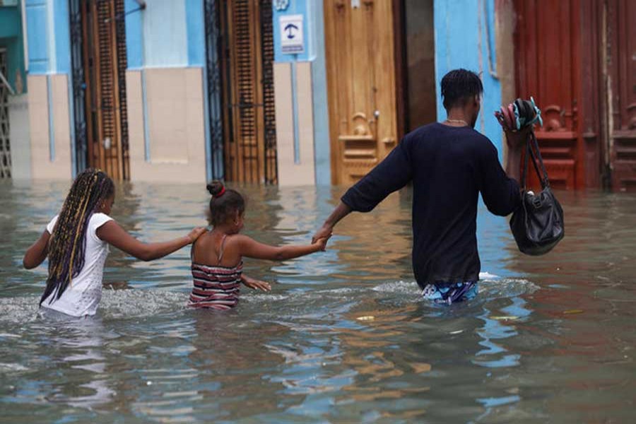 A man and two children wade through a flooded street, after the passing of Hurricane Irma, in Havana, Cuba September 10, 2017. Reuters/File Photo