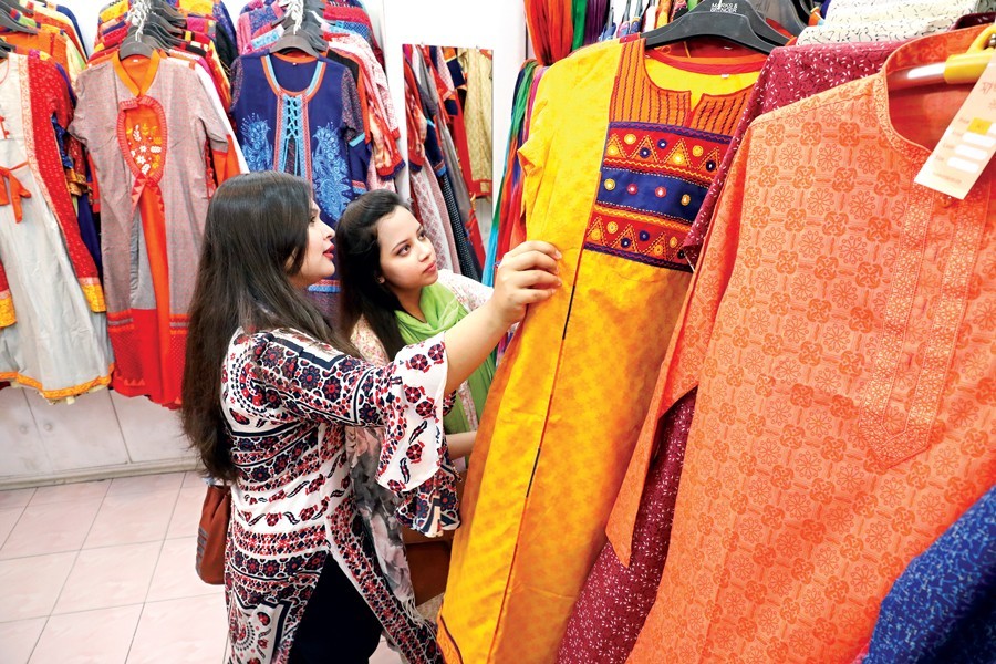 Two shoppers making their choice of dresses at a fashion outlet in Aziz Super Market on Tuesday, as the city dwellers are racing against time doing shoppong with the Eid-ul Fitr few days away — FE Photo