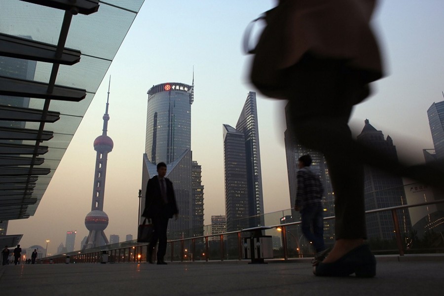 People walk along an elevated walkway at the Pudong financial district in Shanghai - Reuters file photo