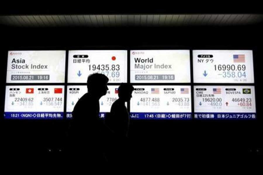 People walk past an electronic board displaying various Asian countries' stock price index and world major index outside a brokerage in Tokyo, Japan, August 21, 2015. Reuters/File Photo