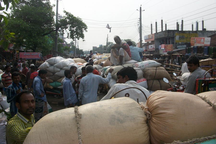 Traders at the Dakbangla Market unloading their goods occupying the Jhenidah-Chuadanga Highway in Jhenidah Sadar on Thursday 	— FE Photo