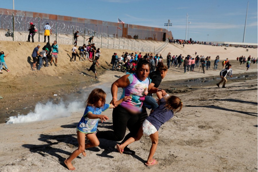 A migrant family, part of a caravan of thousands traveling from Central America en route to the United States, run away from tear gas in front of the border wall between the US and Mexico in Tijuana, Mexico on Monday — Reuters photo