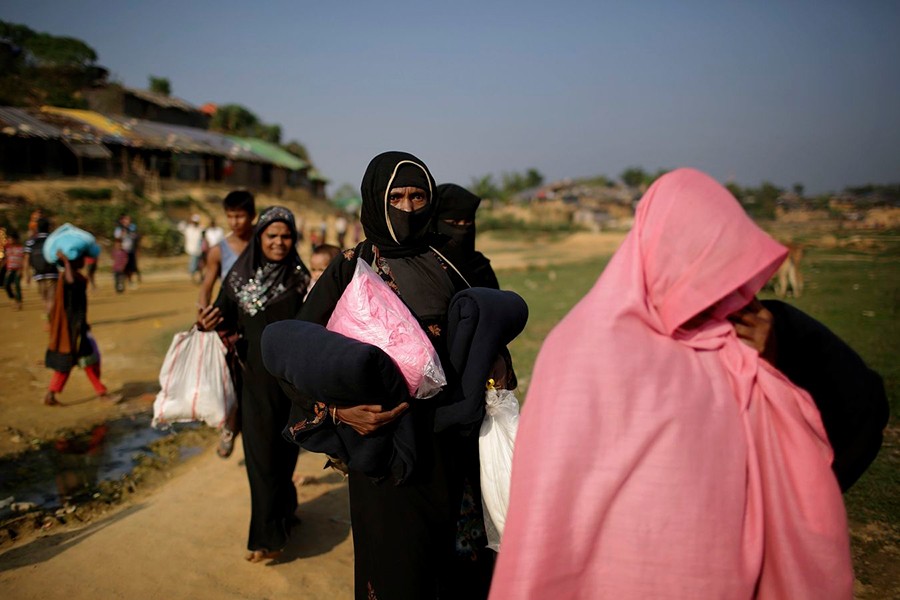 Rohingya Muslim women carry blankets and other supplies they collected from aid distribution centers in Kutupalong refugee camp in Bangladesh on Novermber 21, 2017 — AP file photo used for representation