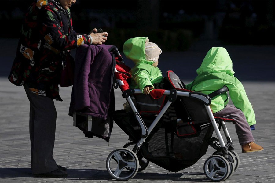 FILE PHOTO: An elderly woman pushes two babies in a stroller in Beijing, China October 30, 2015 - REUTERS/Kim Kyung-Hoon/File Photo