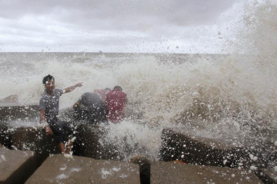 Waves crash into people sitting by the shore of the Bay of Bengal before cyclone Mahasen approaches in Chittagong May 16, 2013. Reuters/Files