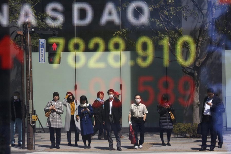 People are reflected on the electronic board of a securities firm in Tokyo, Tuesday, April 2, 2019. (AP Photo)