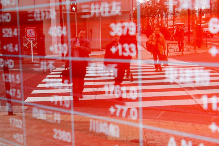 Pedestrians are reflected on an electronic board showing stock prices outside a brokerage in Tokyo, Japan, December 27, 2018. Reuters/Files
