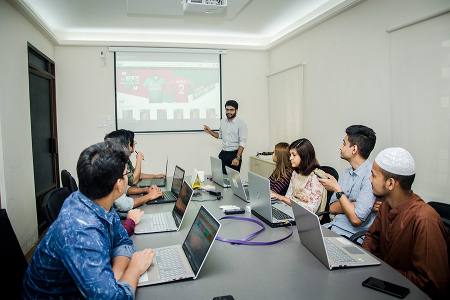 Mehedi Hasan (standing), co-founder of Aadi, an e-commerce company, is seen in a meeting with his leadership team