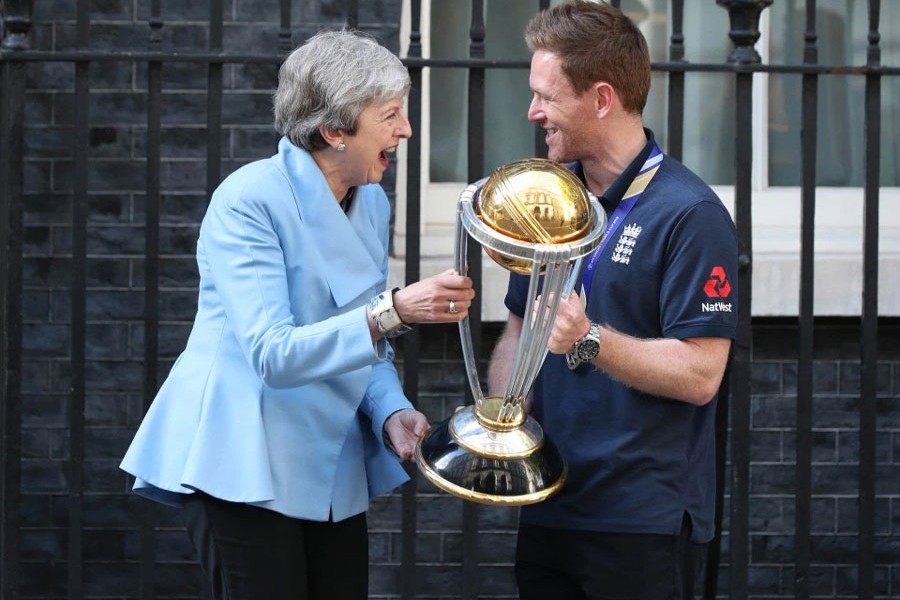 British Prime Minister Theresa May laughing as she's handed the trophy by England cricket captain Eoin Morgan