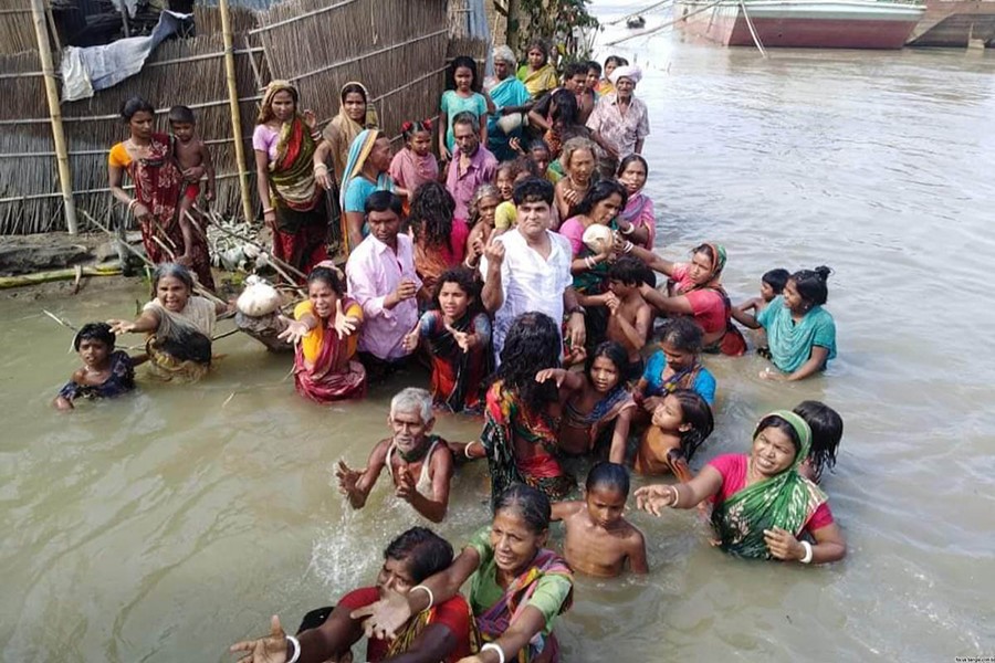 A group of flood-hit people eagerly waiting to receive food during a relief distribution programme in Chilmari under Kurigram on Sunday — Focus Bangla photo