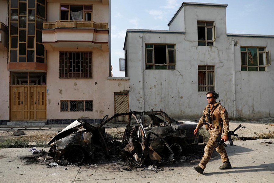 An Afghan security force walks past a burnt vehicle after Sunday’s attack at the site in Kabul, Afghanistan on July 29, 2019 — Reuters photo