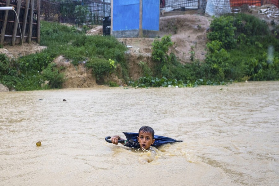In this July 2019 photo, a young boy in Bangladesh navigates a river swollen from days of monsoon rain. He is collecting plastic bottles washed into the river to sell to recyclers to help his family purchase food. UNICEF/Thomas Nybo