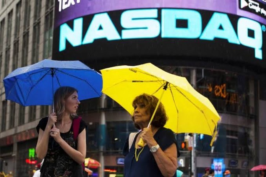Two women hold umbrellas as they walk past the Nasdaq MarketSite in New York's Times Square, August 22, 2013. Reuters/Files