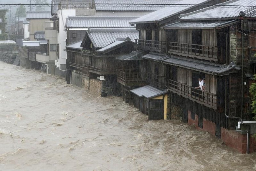 Men watch the swollen Isuzu River due to heavy rain caused by Typhoon Hagibis in Ise, central Japan, in this photo taken by Kyodo October 12, 2019. Mandatory credit Kyodo/via REUTERS