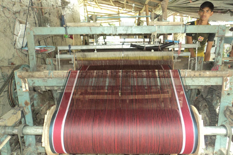 A young weaver weaving gamchha at a small factory in Adamdighi upazila of Bogura district       	— FE Photo