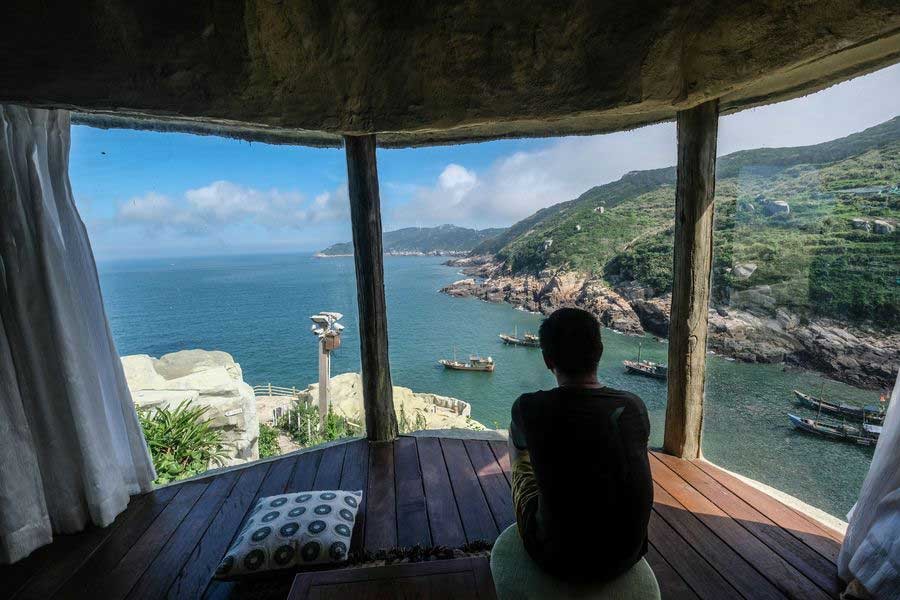 A tourist enjoys the scenery of the ocean in a hotel built on the edge of a cliff at Nanji island, Wenzhou, east China's Zhejiang province, July. 17, 2019. (Xinhua/Xu Yu)