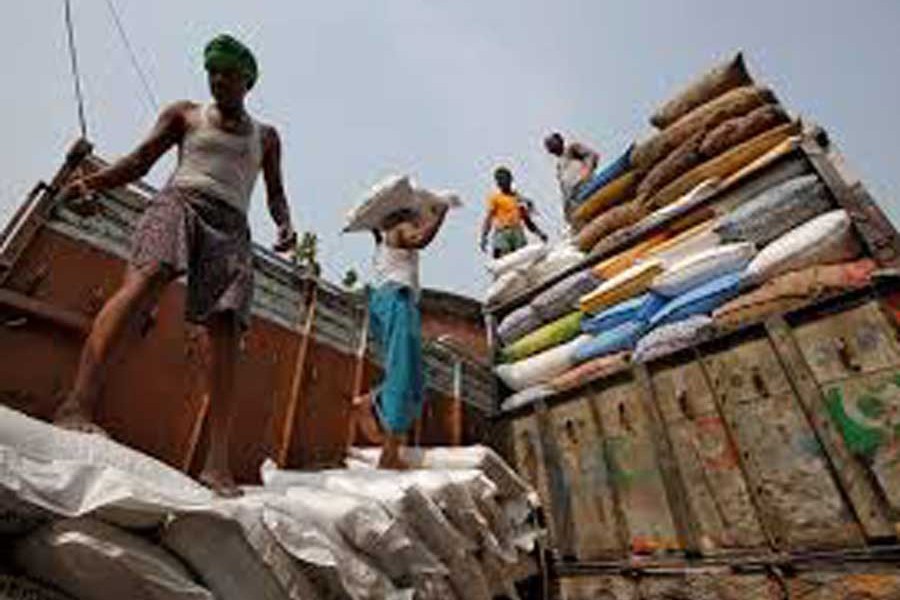 A labourer carries a sack filled with sugar to load it onto a supply truck at a wholesale market in Kolkata, India	— Reuters