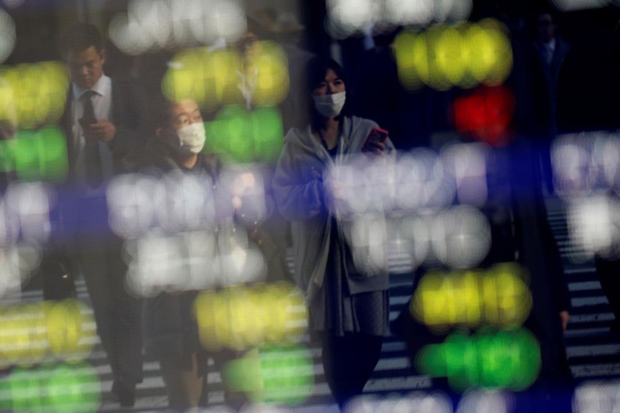 Pedestrians wearing facial masks are reflected on an electric board showing stock prices outside a brokerage at a business district in Tokyo, Japan January 30, 2020. Reuters/Files