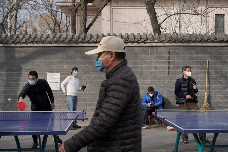 People wearing face masks playing table tennis at a park in Beijing, China, on Friday following an outbreak of the novel coronavirus in the country. -Reuters Photo