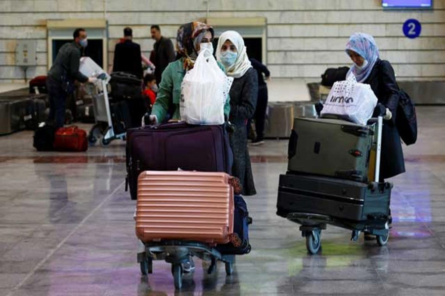 Iraqi passengers wearing protective face masks wheel their luggage upon their arrival from Iran, at Najaf airport, Iraq Mar 5, 2020. REUTERS