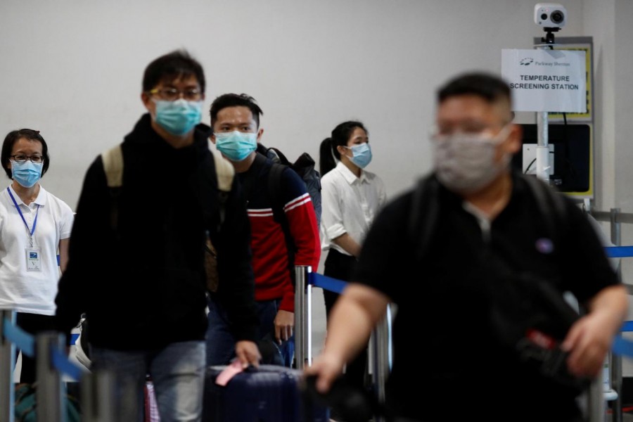 FILE PHOTO: Passengers arriving from Batam, Indonesia, pass a temperature screening station at the Singapore Cruise Center, following the coronavirus outbreak in Singapore March 5, 2020. REUTERS/Edgar Su