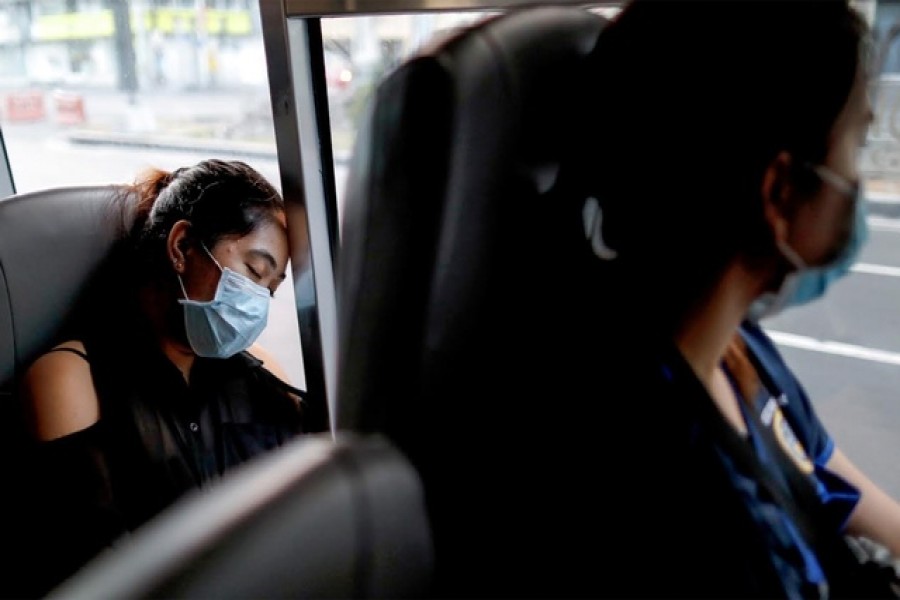 A medical worker wearing a protective mask sleeps inside a free shuttle service for healthcare workers following the suspension of mass transportation in Metro Manila to contain the spread of coronavirus disease (COVID-19), in Manila, Philippines, Mar 30, 2020. REUTERS