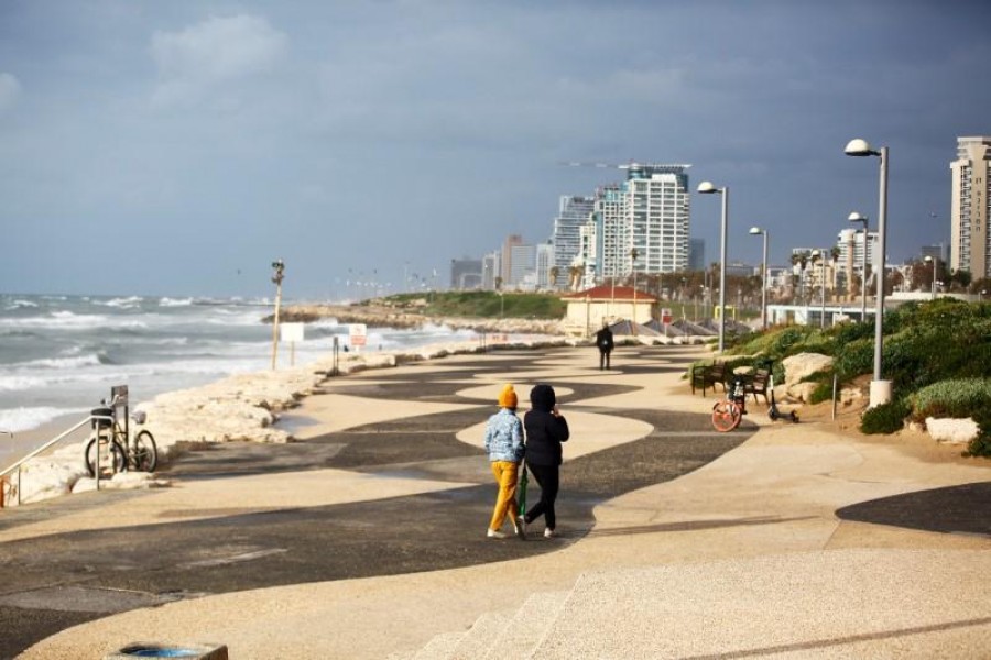 FILE PHOTO: Women walk by the shore of the Mediterranean Sea after Israel's health ministry urged people not to leave their homes except to seek "vital needs and services" in new directives in precautionary measures against coronavirus, in Tel Aviv, Israel March 17, 2020. REUTERS/Corinna Kern