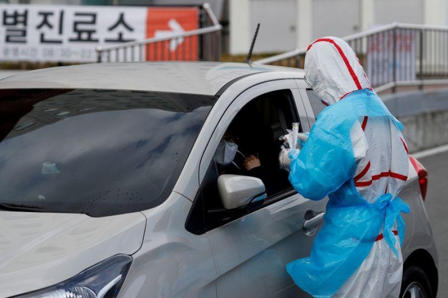 FILE PHOTO: A medical staff member in protective gear prepares to take samples from a visitor at a 'drive-thru' testing center for the novel coronavirus disease of COVID-19 in Yeungnam University Medical Center in Daegu, South Korea, March 3, 2020. REUTERS/Kim Kyung-Hoon