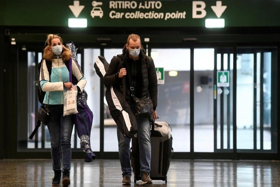 People wearing protective masks walk in Malpensa airport near Milan, Italy, March 09, 2020. — Reuters/Files