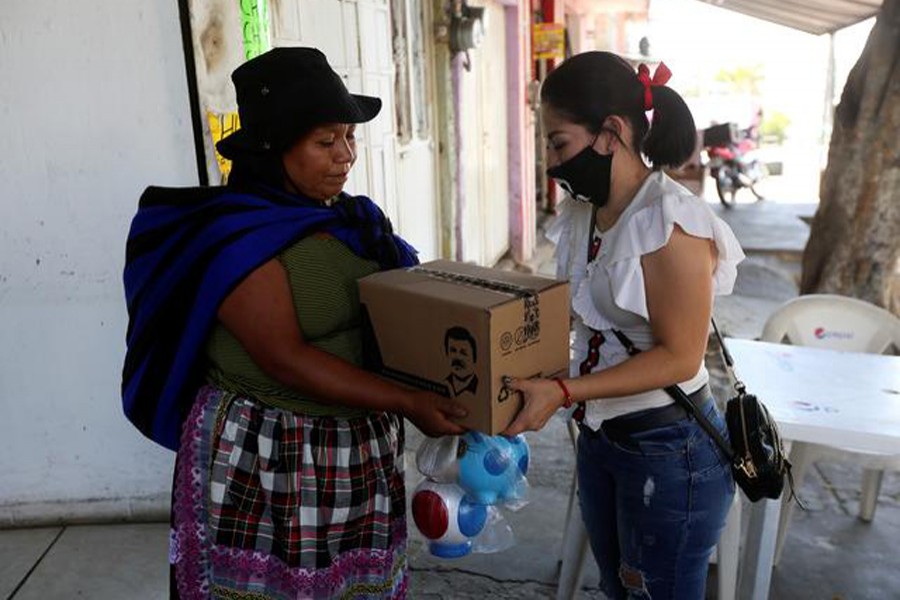 An employee of the clothing brand "El Chapo 701", owned by Alejandrina Gisselle Guzman, daughter of the convicted drug kingpin Joaquin "El Chapo" Guzman, hands out a box with food, face masks and hand sanitisers to an elderly woman as part of a campaign to help cash-strapped elderly people during the coronavirus disease (COVID-19) outbreak, in Guadalajara, Mexico on April 16, 2020 — Reuters photo